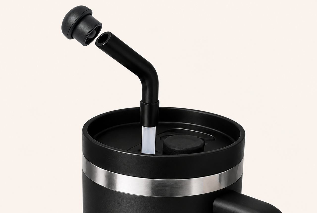 Black stainless steel tumbler with angled reusable straw and magnetic silicone straw topper hovering above the opening, demonstrating leak resistant straw protection and magnetic attachment for 10mm–12mm tumbler straws during travel and everyday use.