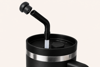 Black stainless steel tumbler with angled reusable straw and magnetic silicone straw topper hovering above the opening, demonstrating leak resistant straw protection and magnetic attachment for 10mm–12mm tumbler straws during travel and everyday use.