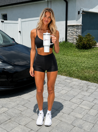 Woman holding a white TickTrend 40 oz insulated tumbler with handle and straw outdoors in front of a home.