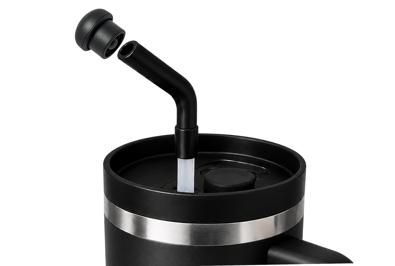 Black stainless steel tumbler with an angled reusable straw and a magnetic silicone straw cover cap positioned above the straw opening, showing the magnetic attachment and compatibility with most 10–12mm reusable straws.